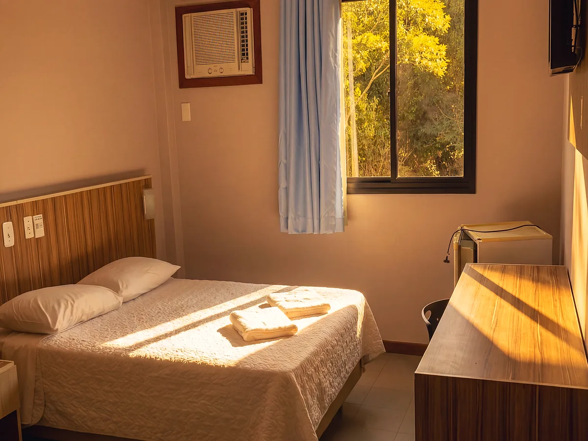 Quarto Standard do Hotel Rinkão, com cama de casal, ar-condicionado e mesa de trabalho